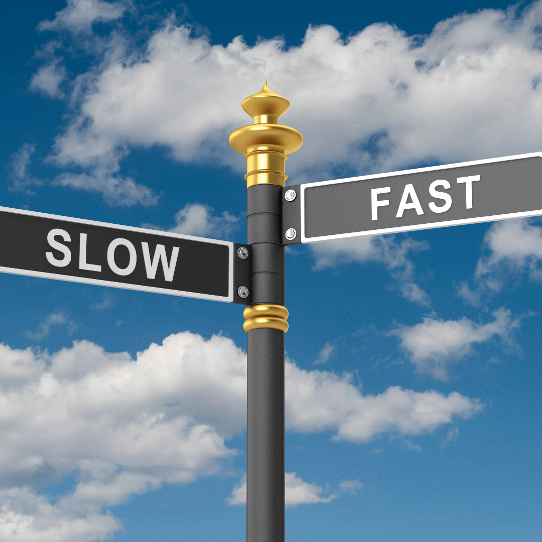 Street sign with "slow" on the left and "fast" on the right with a blue partly cloudy sky in the background