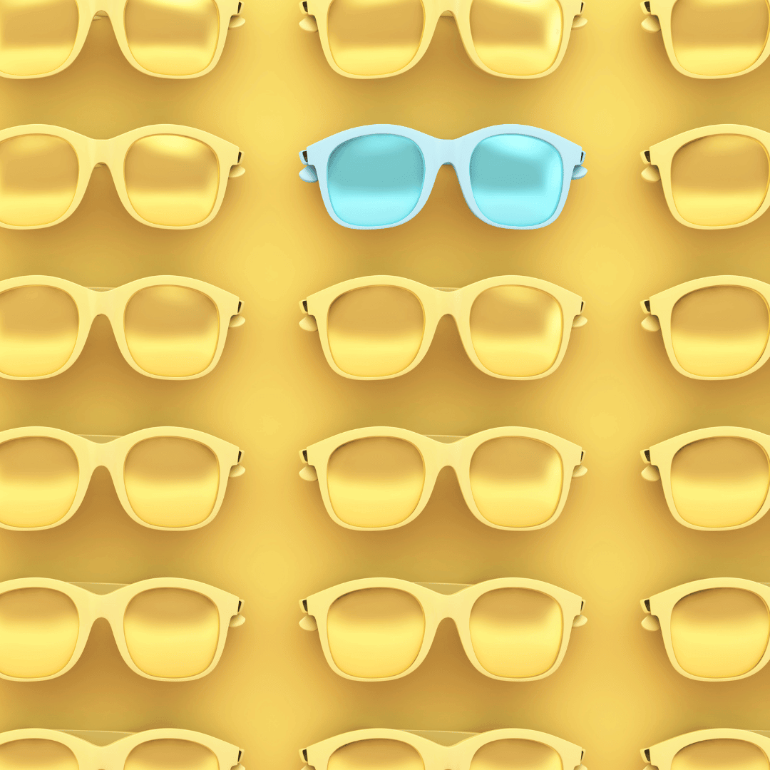 a pair of blue sunglasses among a wall of yellow sunglasses with a yellow background