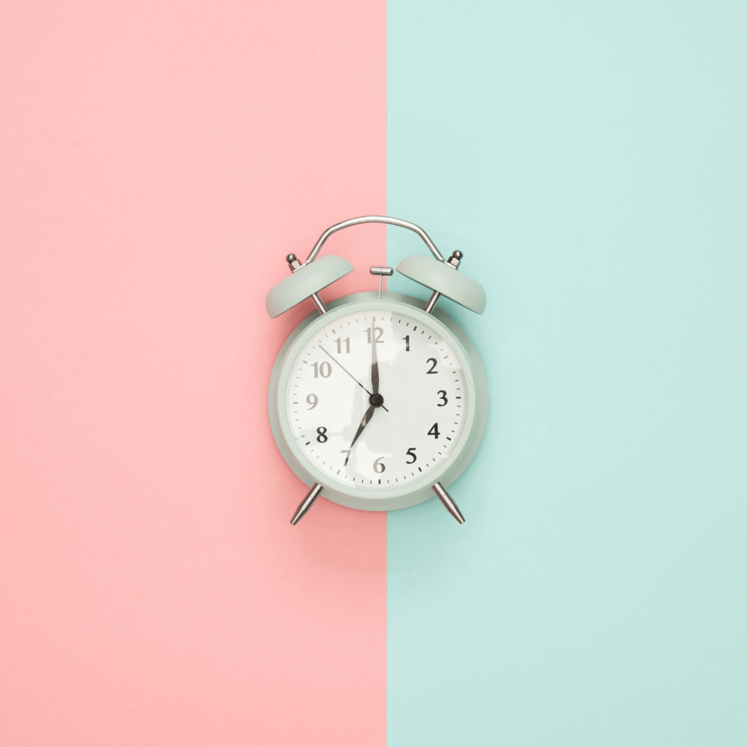 Analog clock with a background splt down the middle pink on the left and blue on the right